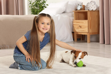 Cute girl playing with her dog in bedroom at home. Adorable pet