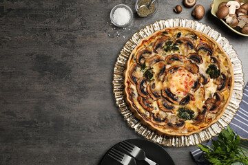 Delicious quiche with mushrooms and ingredients on dark grey table, flat lay. Space for text