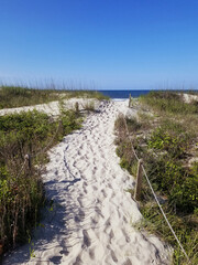 Sandy walking path through the dunes leading to the beach in Oak Island North Carolina