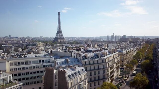 Aerial cinematic drone Paris France Eiffel Tower famous historic landmark from a distance mid day late summer romantic blue sky surrounded by buildings and car traffic backward  motion