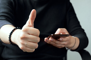 Thumb up. Satisfied man reacting positively to something he sees on his cell phone by raising the thumb of his right hand. Approval of an Internet user before a service, an image or a piece of news.