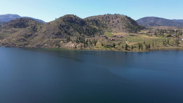Drone aerial crossing Skaha Lake toward Kaleden in the Okanagan Valley in spring