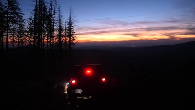 Off road vehicle slowly driving through obstacles on a mountain road during sunset in summer.
