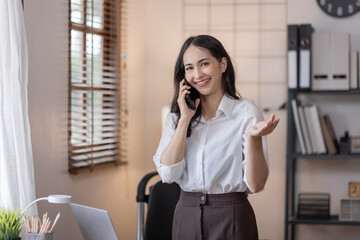 Happy caucasian young Asian woman using smart phone cellphone for calls, social media, mobile application online in office money financial planning Business And Education Concept.