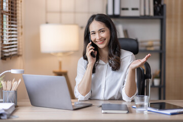 Fototapeta premium Happy caucasian young Asian woman using smart phone cellphone for calls, social media, mobile application online in office money financial planning Business And Education Concept.