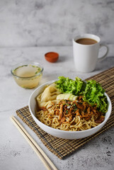 Mie ayam, noodles with chicken and vegetables, Indonesian traditional food in grey texture background.
