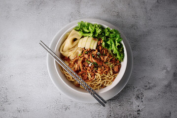 Mie ayam, noodles with chicken and vegetables, Indonesian traditional food in grey texture background.