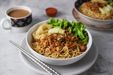 Mie ayam, noodles with chicken and vegetables, Indonesian traditional food in grey texture background.