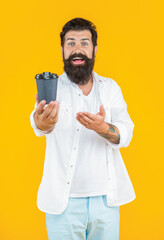 selective focus photo of guy with morning coffee cup, presenting product.