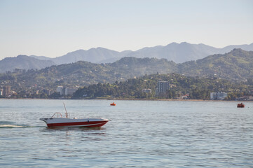 Obraz premium A powerboat sailing along the hilly coast in the morning haze