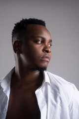 Obraz premium African black man model with six pack in unbuttoned checkered shirt, isolated against a beach rocks, sand and blue sky.