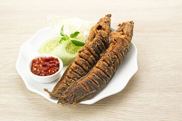 Lele Goreng or Fried Catfish, Indonesian traditional food. Served with chilli paste (sambal), cucumber and cabbage

