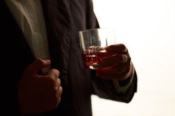 Businessman in black suit holding glass of whiskey Celebrate company success close-up
