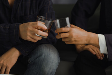 Businessman in black suit holding glass of whiskey Celebrate company success close-up