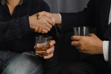Businessman in black suit holding glass of whiskey Celebrate company success close-up