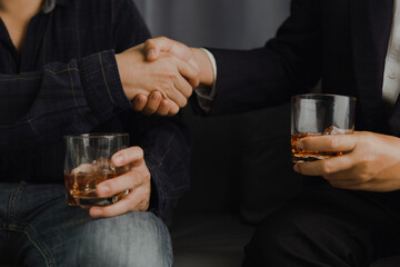 Businessman in black suit holding glass of whiskey Celebrate company success close-up