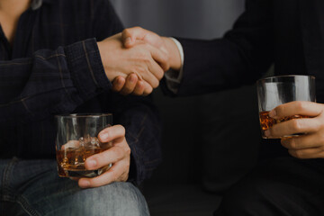 Businessman in black suit holding glass of whiskey Celebrate company success close-up