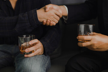Businessman in black suit holding glass of whiskey Celebrate company success close-up