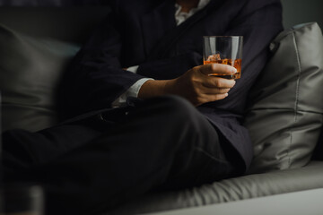 Obraz premium Businessman in black suit holding glass of whiskey Celebrate company success close-up