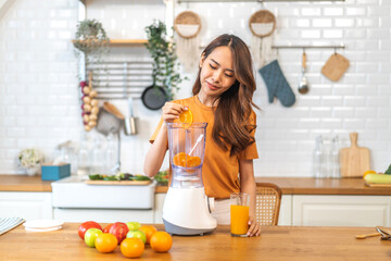 Portrait of beauty healthy asian woman making orange fruit smoothie with blender.young girl preparing cooking detox cleanse with fresh orange juice in kitchen at home.Diet concept.healthy drink