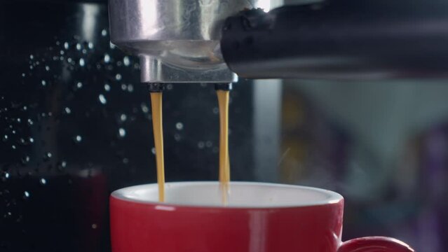 Pouring coffee stream from machine in cup. Home making hot Espresso. Using filter holder. Flowing fresh ground coffee. Drinking roasted black coffee in the morning. Footage B Roll shot of coffee pour.