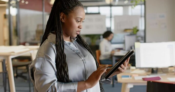 Portrait of happy african american casual businesswoman using tablet smiling at office, slow motion