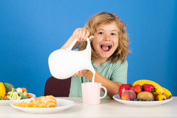 Excited kid with dairy milk. Healthy child pours milk from jug.