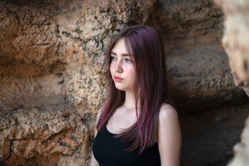 Street summer portrait of a 15-year-old girl against a rock.