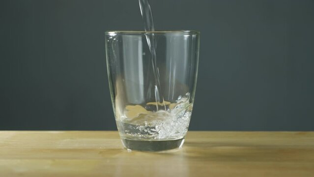Shoot of water pouring into transparent glass on Table with clear background. Drinking water is pouring into the glass. B Roll slow motion 4k.