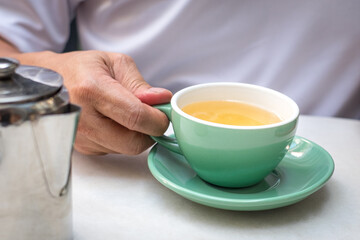 Man holding a cup of chamomile tea. Close up view.