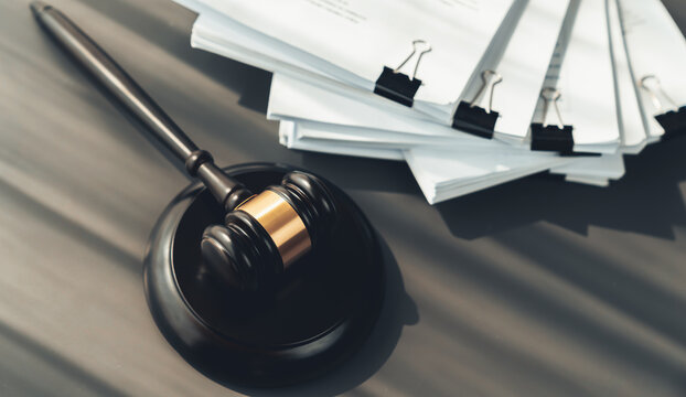 Closeup top view black wooden gavel hammer and legal document on wooden office desk background as justice and legal system for lawyer and judge, Legal authority and fairness in trials. equility