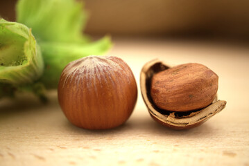 Unshelled and cracked hazelnuts near green leaves