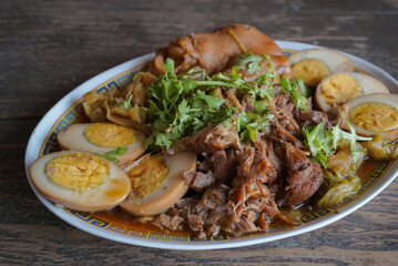 Thai Braised pork knuckle and eggs with spices and vegetable on wooden table