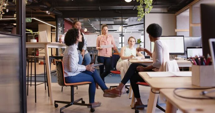 Diverse female business creatives discussing project at work, in slow motion