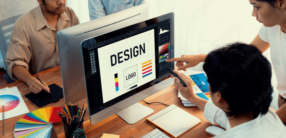 Poster Graphic designer work on computer laptop and with graphic drawing pen while brainstorming unique design with professional graphic team in modern digital studio workplace. Panorama shot. Scrutinize