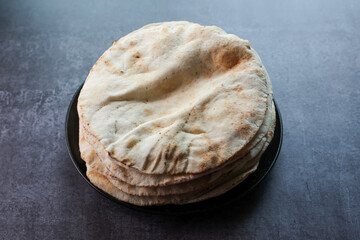 Freshly baked arabic or Pakistani flat bread Kuboos or roti on a black background. Kuboos or khubz...