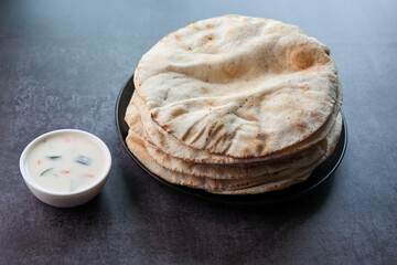 Freshly baked arabic or Pakistani flat bread Kuboos or roti on a black background. Kuboos or khubz...