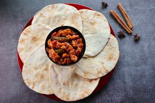 Freshly baked arabic or Pakistani flat bread Kuboos or roti on a black background. Kuboos or khubz fresh pita bread with chilly chicken curry