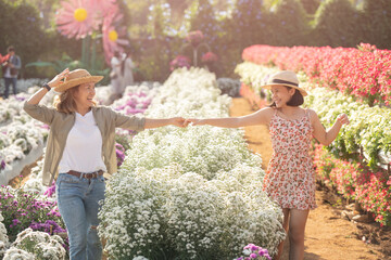 Fototapeta na wymiar friendship between mom and daughter. romantic portrait of young woman and her daughter are playing and walking in a field with rich flowers. creative portrait of a family in nature. happy earth day.