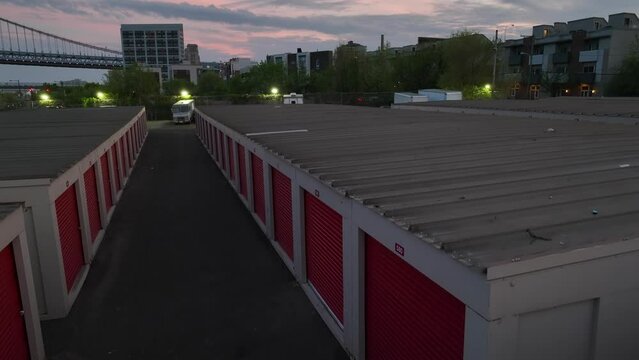 Aerial rising shot of self storage units in American city. Bridge and apartments in background. USA storage units theme.