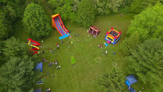 Aerial drone view of children playing on inflatable toys outdoors.