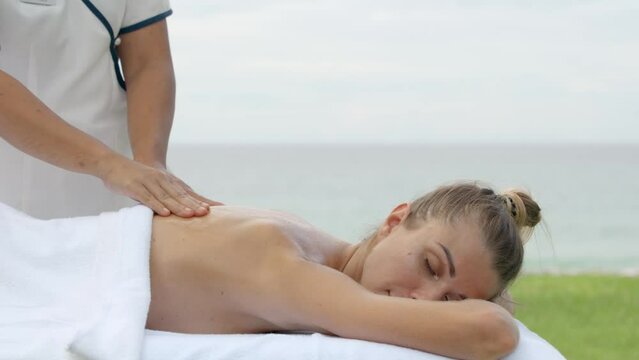 Woman reciving relaxing massage on special table beside the outdoor 