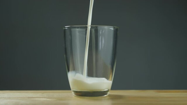 Shoot of Milk Poured Into A Transparent Glass on Table with clear background. B Roll slow motion 4k.