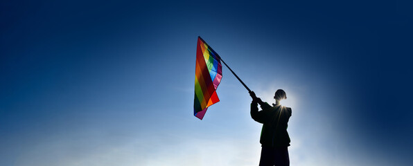 Rainbow flag, LGBT symbol, raising  against clearly bluesky background, copy space, concept for LGBT people celebrations in pride month around the world.