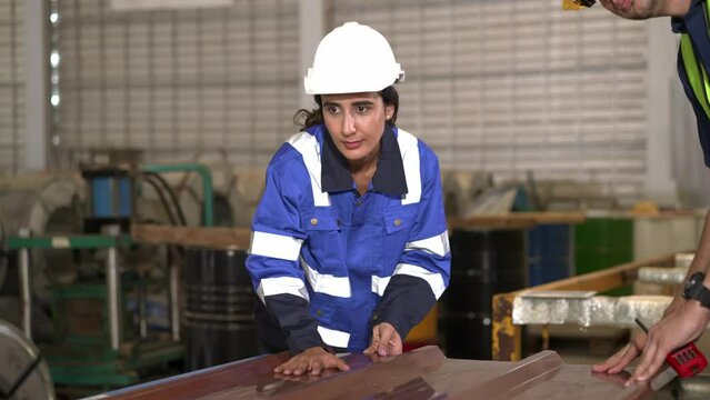 Young inspector female and foreman checking quality of metal sheet in factory