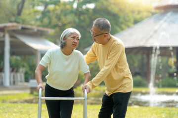 Obraz premium Husband helps his elderly wife use a walker to learn to walk elderly couple Asian elderly couple giving love to each other smiling happily love and care for each other