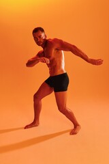 Fototapeta na wymiar Man bodybuilder boxer muscle workout with naked torso with abs posing in studio. Advertising, sports, active lifestyle, colored yellow light, competition, challenge concept. 