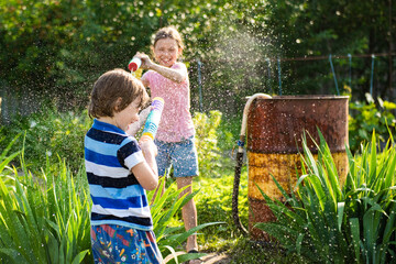 Two little kids playing with water guns on hot summer day. Cute children having fun with water on the backyard. Funny summer games for kids. Family having water fight outdoors