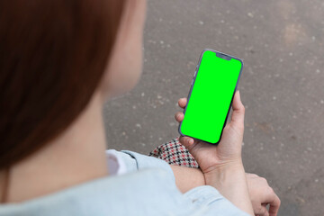 A female holds a smartphone with a blank screen to replace it with a text message or informational...