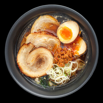 Asian ramen noodle soup with Chashu (Japanese braised pork belly), Nitamago egg, sliced spring onion, Ajitsuke Menma isolated on black background, square ratio, top view